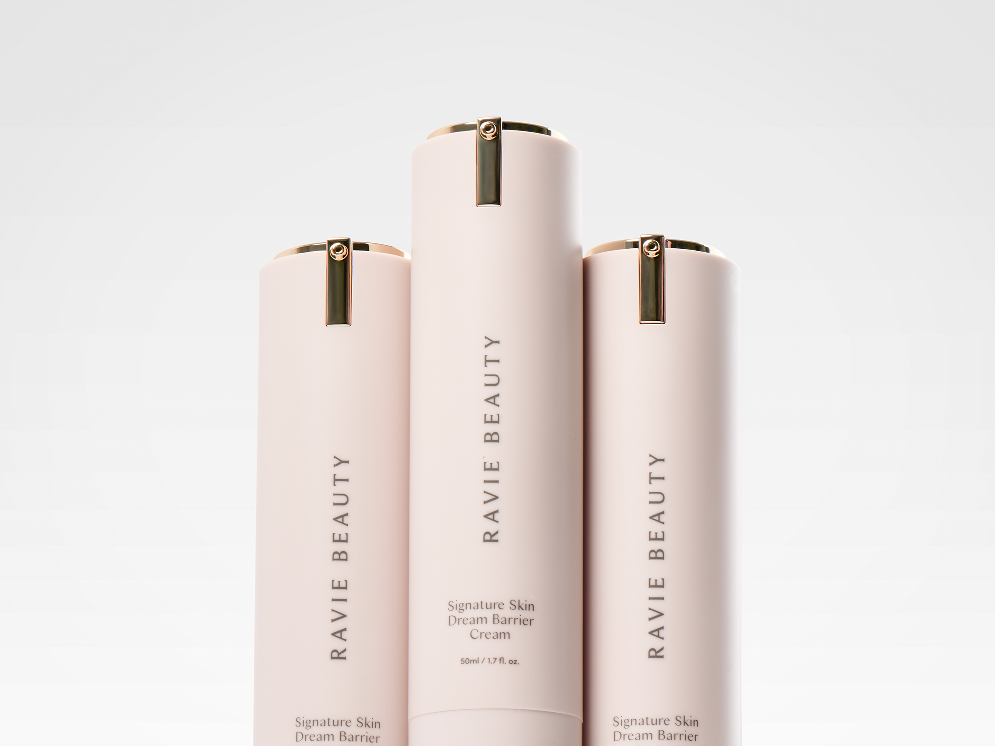 Three Ravie Beauty Signature Skin Dream Barrier Cream airless pump tubes lined up against a clean pale background, soft studio light, minimal editorial product shot
