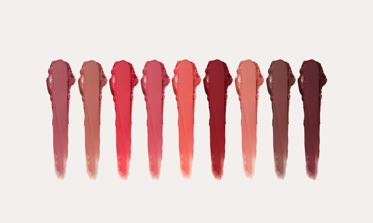 Ravie Beauty Effortless Lips full nine-shade range arranged as three trios (Original, Signature, Classic), cool grey tubes with champagne gold bullets, soft natural light