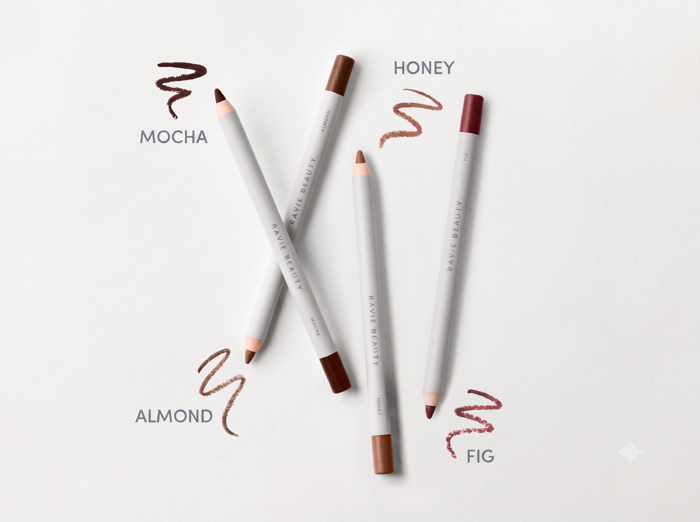 Ravie Beauty Soft Definition Longwear Lip Liner pencils in Honey, Almond, Fig, and Mocha lined up on a clean surface, synthetic wood casing visible, soft natural light