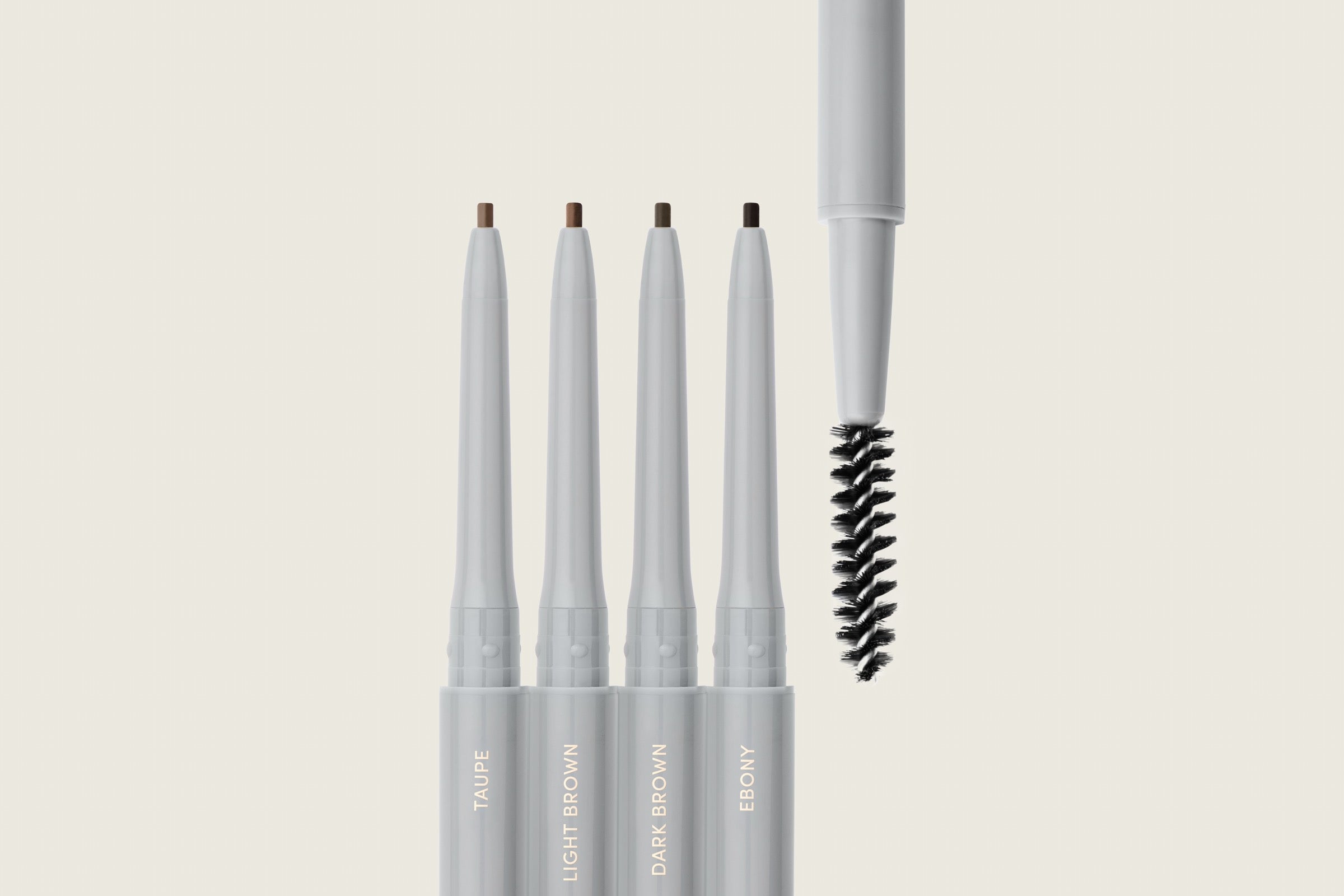 Ravie Beauty Easy Everyday Brow Pencil close-up with spoolie end visible, twist-stop mechanism, editorial styling on a clean surface