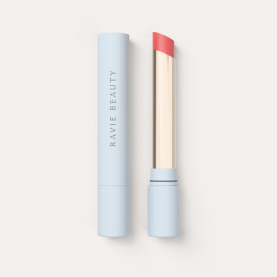 An open tube beside its cap. Ravie Beauty Effortless Lips™ Sheer-Buildable Lip Color in Poppy 